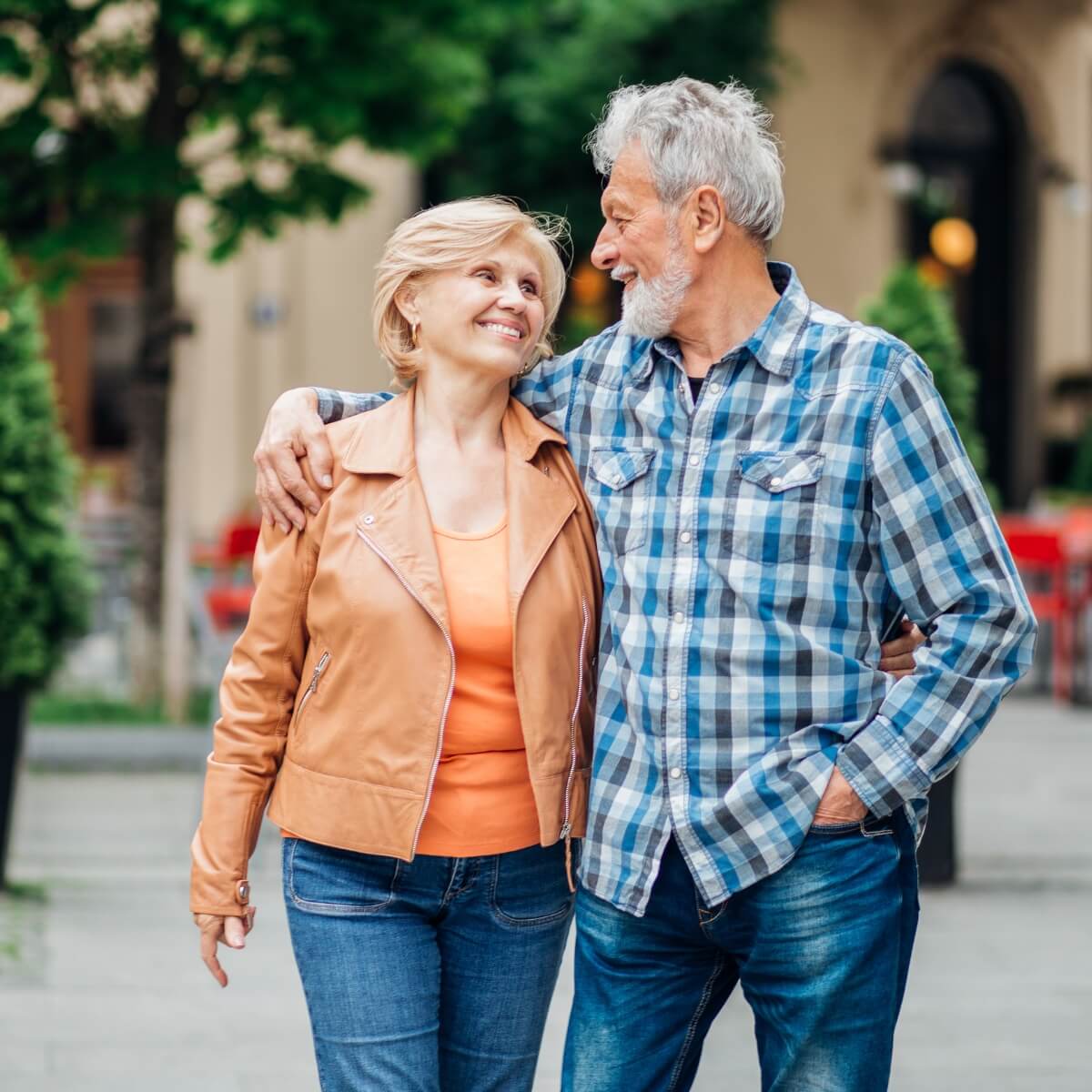 male and female couple in their 50s walking in the park looking at each other lovingly